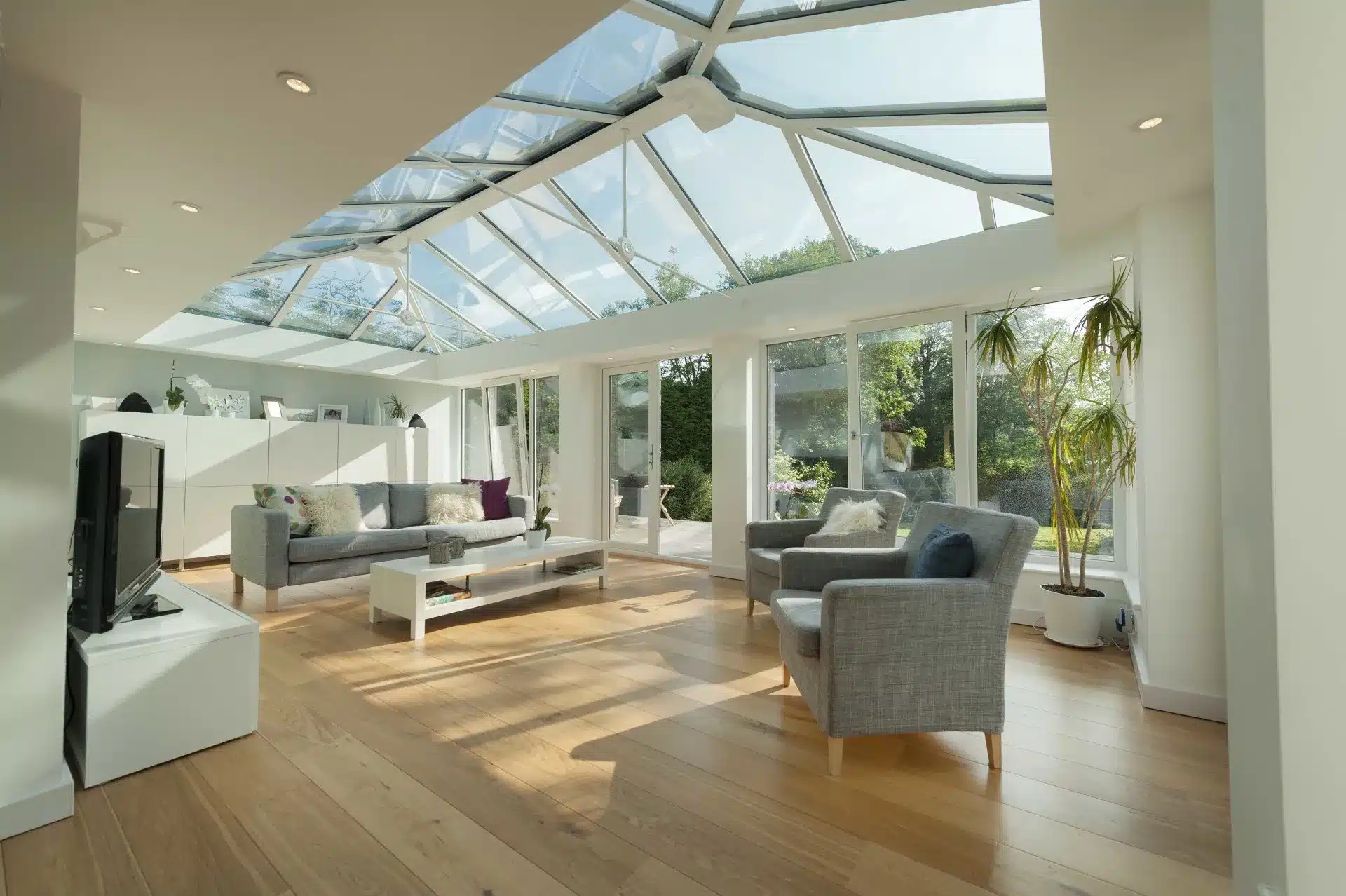 Bright orangery interior with a glazed roof and full-height windows