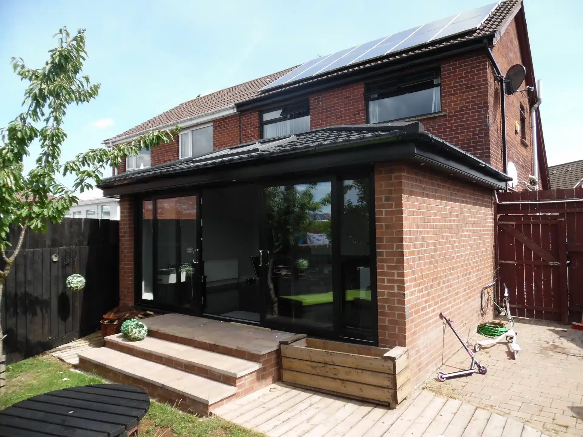 Rear sunroom extension with black-framed glazing and tiled roof