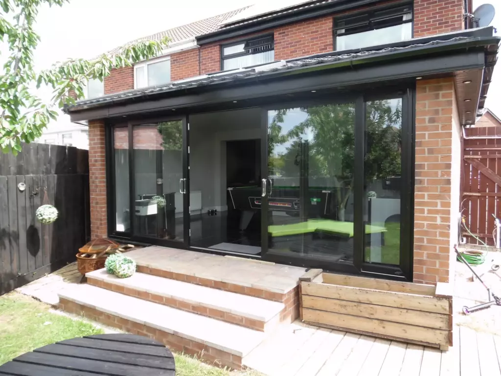 Rear view of a sunroom with wide black-framed doors