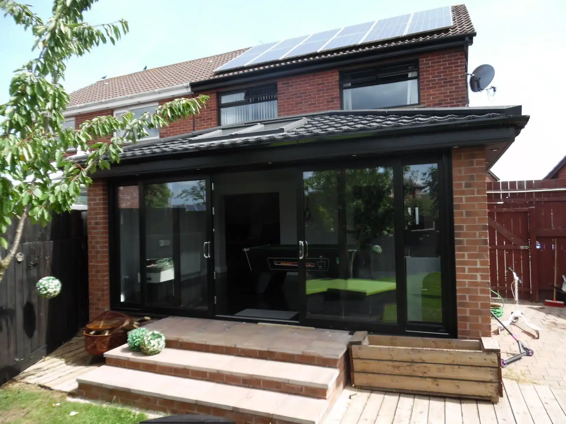 Rear view of a sunroom with black-framed glazing and tiled roof