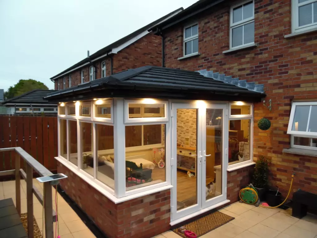 Sunroom extension with a tiled roof illuminated at dusk