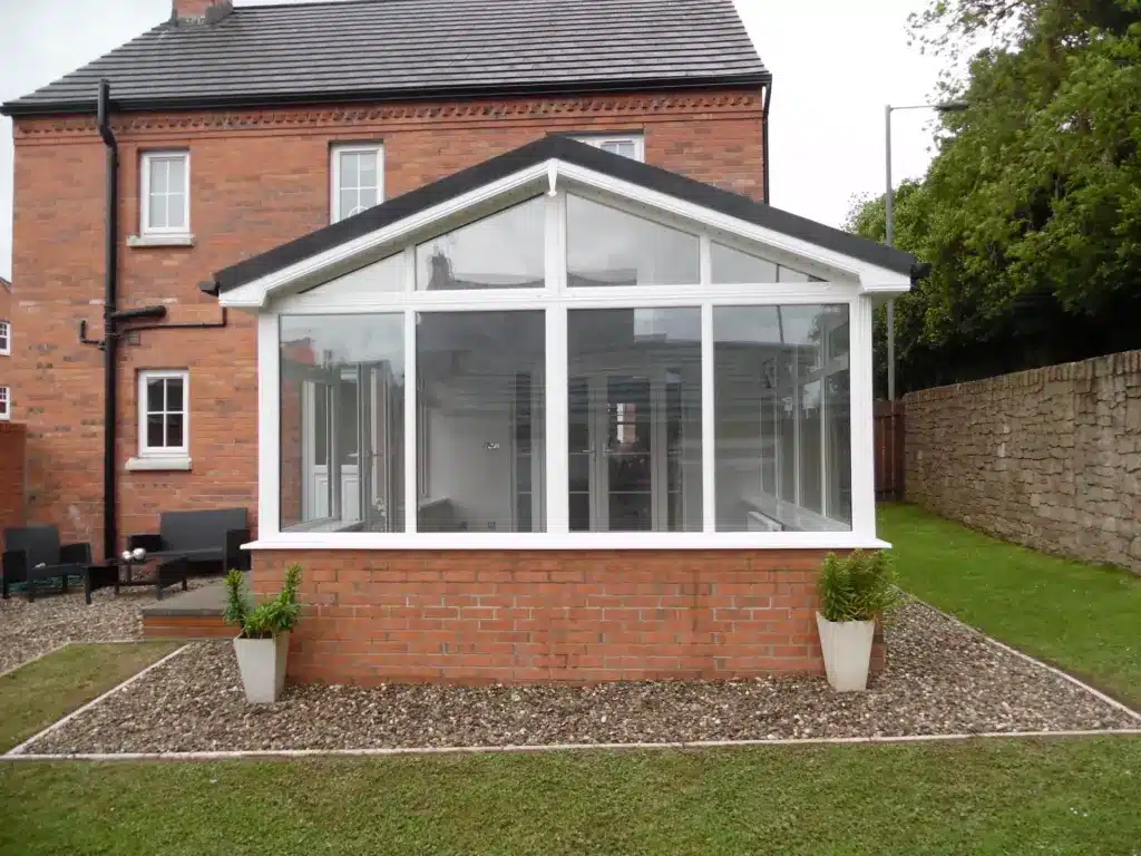 Front view of a white sunroom extension with a glazed roof