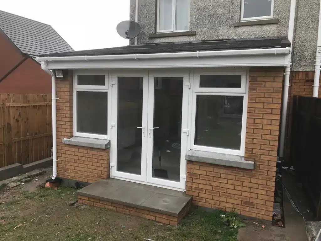 Brick sunroom extension with grey tiled roof and French doors